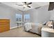 Cozy bedroom with a ceiling fan, large window, and a combination of carpet and tile flooring at 10783 Vestone St, Las Vegas, NV 89141