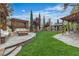 Well-maintained backyard features a cozy fire pit, manicured lawn, and shaded pergola with seating at 10988 Wonder Hills St, Las Vegas, NV 89141