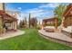 Beautiful backyard with manicured lawn, built-in seating, pergola, and fire pit for outdoor relaxation at 10988 Wonder Hills St, Las Vegas, NV 89141