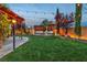 Manicured backyard featuring string lights, a pergola, fire pit, and lush lawn at 10988 Wonder Hills St, Las Vegas, NV 89141