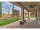 Covered patio with stone flooring, ceiling fan, columns, and manicured backyard at 10988 Wonder Hills St, Las Vegas, NV 89141
