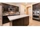 Modern kitchen with an island, stainless steel appliances, dark wood cabinets, and neutral countertops at 1313 Gallery Oaks Dr, Las Vegas, NV 89123