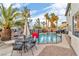 Inviting backyard oasis with pool, palm trees, patio seating, and secure pool fence at 1486 Neyland Dr, Henderson, NV 89012