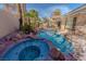 Inviting backyard pool and spa surrounded by rock features and lush greenery at 1720 Sand Storm Ct, Henderson, NV 89074