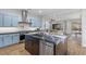 Modern kitchen with stainless steel appliances, stylish backsplash, an island with dark cabinets, and light blue cabinets at 26 Moraine Dr, Henderson, NV 89052