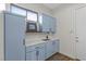 Well-lit laundry room featuring blue cabinets, white countertops, a window for natural light, and hardwood floors at 26 Moraine Dr, Henderson, NV 89052