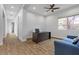 Home office features a dark desk, blue sofa, hardwood floors, a ceiling fan, and large window at 26 Moraine Dr, Henderson, NV 89052