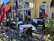 Elegant outdoor bistro seating with white tablecloths, dark wicker chairs, and a red umbrella at 30 Strada Di Villaggio # 439, Henderson, NV 89011