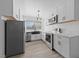 A modern kitchen featuring white cabinets, stainless steel appliances, and a farmhouse style sink with wood-look flooring at 3597 Arville St # 201B, Las Vegas, NV 89103