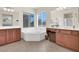 Bright bathroom with a soaking tub, dual sinks, wooden cabinets, and a large window at 3925 Kettle Falls Ave, North Las Vegas, NV 89085