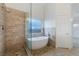 Elegant bathroom with a soaking tub, stone-tiled shower, and modern fixtures at 827 Happy Sparrow Ave, Henderson, NV 89052