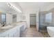 Luxurious primary bathroom featuring double sinks, granite counters, walk-in shower, and soaking tub at 827 Happy Sparrow Ave, Henderson, NV 89052