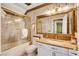 Bathroom with a marble countertop vanity, a large mirror, and a glass-enclosed tub and shower at 8988 Dusseldorf Way, Las Vegas, NV 89147