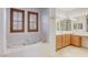 Bathroom featuring a soaking tub with tile surround and wooden vanity with large mirrors at 9160 Moose Country Pl, Las Vegas, NV 89178