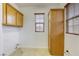 Laundry room with tile flooring, wooden cabinets, and a window with blinds for natural light at 9160 Moose Country Pl, Las Vegas, NV 89178