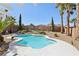 Backyard kidney-shaped pool with desert landscaping, palm trees, and covered patio at 1019 Amber Gate St, Henderson, NV 89002