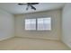 Spacious bedroom with neutral carpet, ceiling fan, and natural light from two windows at 10260 Hawks Wing St, Las Vegas, NV 89178