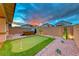 Inviting backyard featuring a putting green, hot tub, desert landscaping, and beautiful sunset at 122 Cabaletta Ln, Henderson, NV 89015