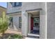 Front entrance showcases covered porch with neutral stucco siding and a vibrant red door at 12728 Feathersong St, Henderson, NV 89044