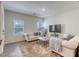 Living room with wood-look floors, a tufted couch, and large windows at 12728 Feathersong St, Henderson, NV 89044