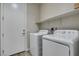 Simple laundry room with side-by-side washer and dryer and a shelf for storage at 221 Mountain Cedar Ct, North Las Vegas, NV 89031