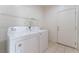 Bright laundry room with a white washer, dryer, storage shelves and tiled floor at 221 Purple Passion Ave, North Las Vegas, NV 89032