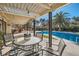 Inviting covered patio with a dining table, overlooking a sparkling pool and lush landscaping at 2412 El Cid Ct, Henderson, NV 89014