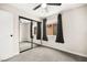 A bright bedroom featuring a mirrored closet door, ceiling fan, and windows with black curtains at 2793 Sandyfalls Way, Las Vegas, NV 89142