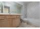 Bathroom with marble-tiled walls, a wooden vanity, and shower-tub combination at 3320 Helmsman Dr, North Las Vegas, NV 89032