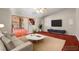 Staged living room featuring a sofa, rug, tv, and open doorway to another room at 4155 Comb Cir, Las Vegas, NV 89104