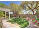 Serene backyard with lush green grass, mature trees, blooming roses, and a covered pergola, perfect for outdoor relaxation at 5240 Adorato Dr, North Las Vegas, NV 89031