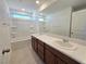Bright bathroom featuring dual sinks, granite countertops, wood cabinets, tub, and walk-in shower at 5748 Avondale Rise Way, Las Vegas, NV 89141