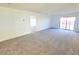 Expansive living room with neutral carpeting, white walls, and sliding glass doors leading to the backyard at 5748 Avondale Rise Way, Las Vegas, NV 89141