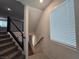 Carpeted staircase featuring modern black railings and a view of a large, sunny window at 5748 Avondale Rise Way, Las Vegas, NV 89141