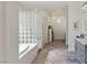 Bright bathroom with a glass block walk-in shower and soaking tub with neutral colored herringbone flooring at 8425 Cambrils Ave, Las Vegas, NV 89178
