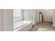 Bright bathroom with a glass block walk-in shower and soaking tub with neutral colored herringbone flooring at 8425 Cambrils Ave, Las Vegas, NV 89178