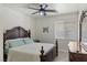 Bedroom with a dark wood bed frame, ceiling fan, and large window at 8425 Cambrils Ave, Las Vegas, NV 89178