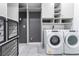 Modern laundry room with white washer and dryer, shelving and tile flooring at 8648 Cloverbelle St, Las Vegas, NV 89166