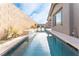 Private lap pool with stone water feature, meticulous landscaping, and clear blue water reflecting the sky at 8648 Cloverbelle St, Las Vegas, NV 89166