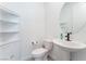 Small, bright powder room featuring a modern pedestal sink, toilet, and built-in shelving unit at 8648 Cloverbelle St, Las Vegas, NV 89166