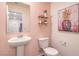 Charming powder room with pedestal sink, toilet, decorative shelf and pink walls for a cozy feel at 9395 Jade Mesa St # Lot 42, Las Vegas, NV 89139