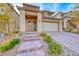 Tan two-story home with well-maintained desert landscaping and a brick driveway and front steps at 12397 Foxtail Run Ave, Las Vegas, NV 89138