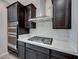 A modern kitchen featuring dark cabinets, stainless steel appliances, and a gas cooktop with a vent hood at 12397 Foxtail Run Ave, Las Vegas, NV 89138