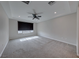 An empty main bedroom featuring carpeted floors, a tray ceiling with a ceiling fan, and a large window at 12397 Foxtail Run Ave, Las Vegas, NV 89138