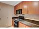 Galley kitchen featuring wood cabinetry, granite countertops, and black appliances at 200 W Sahara Ave # 3009, Las Vegas, NV 89102