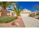 Charming single-story home featuring a well-manicured front yard with desert landscaping and mature palm trees at 2386 Amana Dr, Henderson, NV 89044