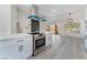 Modern kitchen with white cabinets, stainless steel appliances, a range hood, and wood grain floors at 2553 Showcase Dr, Las Vegas, NV 89134