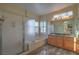 A bathroom featuring a glass shower, soaking tub, and a vanity with dual sinks and decorative light fixture at 3002 Hickory Valley Rd, Henderson, NV 89052