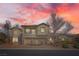 Two-story stucco house at sunset, featuring stone accents, a balcony, and a brick driveway at 3892 Pasilla Ave, Las Vegas, NV 89118