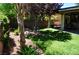 Well-manicured backyard with a covered patio, green lawn, and mature trees for shade at 4047 Cougar Falls Ct, North Las Vegas, NV 89085